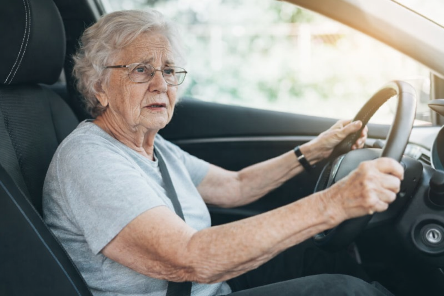 „Ältere Frau fährt Auto und schaut konzentriert auf die Straße Thema Autofahren im Alter und Pflegegrad.“